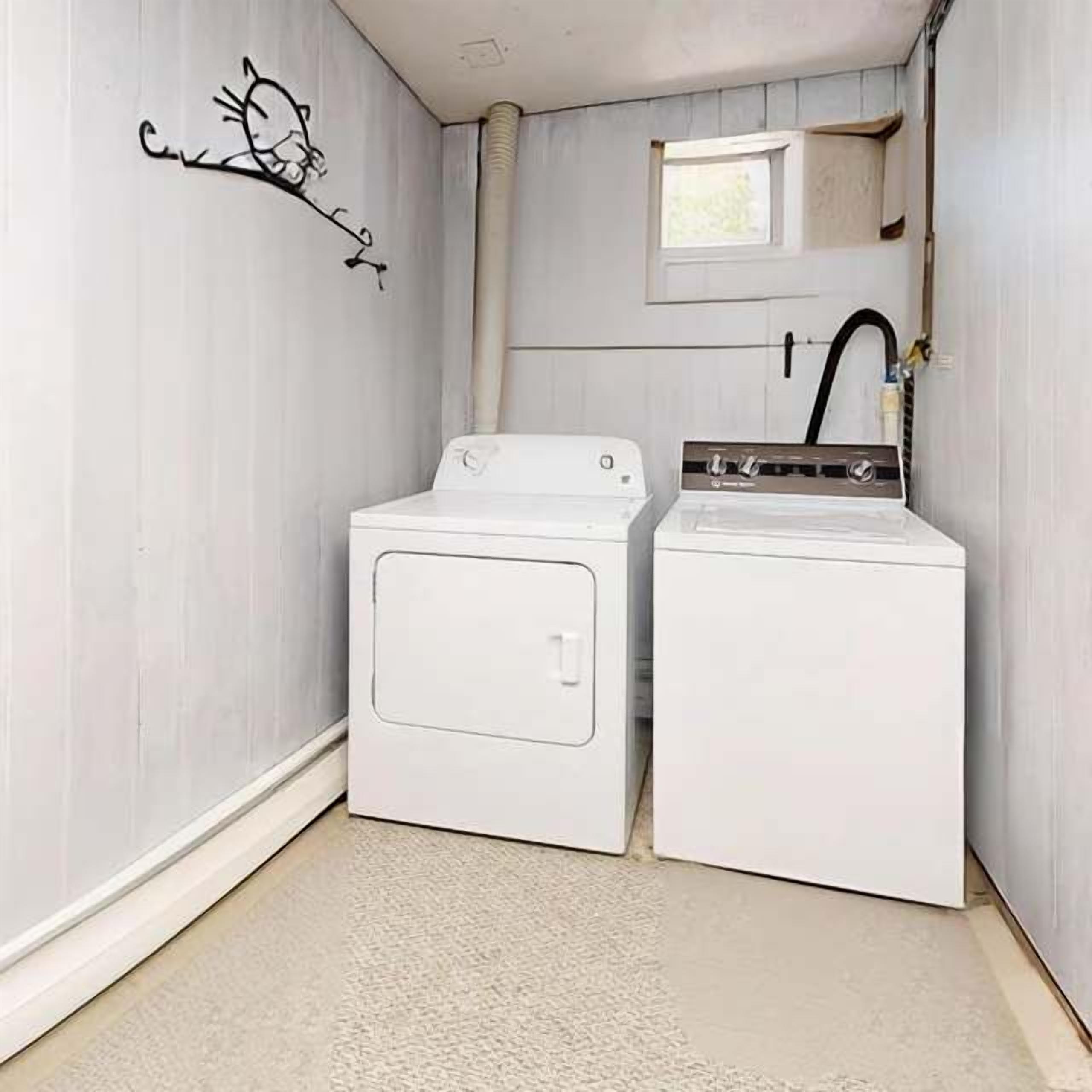 A laundry room with a washing machine and dryer, a small window, and a wall-mounted towel rack.