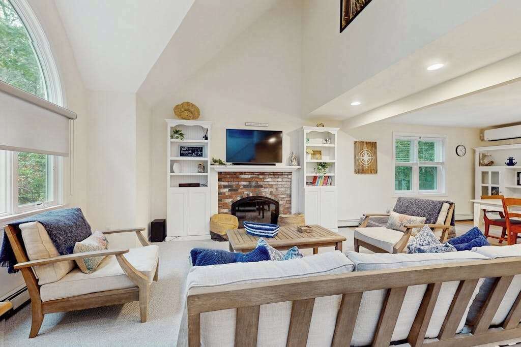 A spacious living room with a fireplace, a television, and a large window.