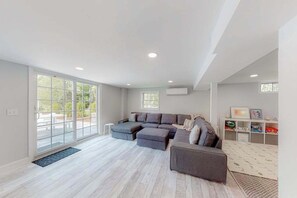 A spacious living area with a sectional sofa, a small ottoman, and a built-in entertainment unit. - Lovely dog-friendly home w/ fireplace, central AC, full kitchen, & washer/dryer (Dennis)