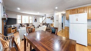 Eine geräumige Küche mit Holzausstattung, einem Esstisch und einem Kühlschrank.