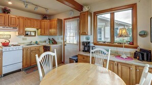 A kitchen with wooden cabinets, a stove, a sink, and a dining table with chairs. - Family Friendly Falmouth Beach House with Ocean Views and BBQ Grill (Falmouth)