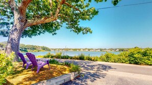 A tree-lined pathway with two purple Adirondack chairs and a view of a lake. - Family Friendly Falmouth Beach House with Ocean Views and BBQ Grill (Falmouth)