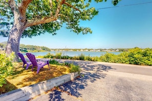 A tree-lined pathway with two purple Adirondack chairs and a view of a lake. - Family Friendly Falmouth Beach House with Ocean Views and BBQ Grill (Falmouth)