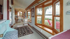 A spacious room with large windows, a dining area, and a view of the outdoors. - Family Friendly Falmouth Beach House with Ocean Views and BBQ Grill (Falmouth)