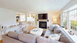 Ein modernes Wohnzimmer mit Kamin, Fernseher und großem Fenster.