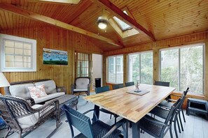 A wooden interior with a dining table, chairs, a sofa, and a painting on the wall. - Spacious house close to town and beach with AC, W/D, games, deck, & grill (Dennis Port)