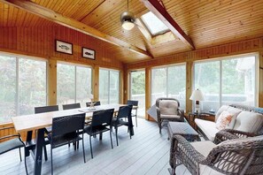 A wooden-paneled room with a dining table, chairs, and wicker furniture. - Spacious house close to town and beach with AC, W/D, games, deck, & grill (Dennis Port)