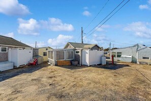 A row of small, single-story houses with attached garages, a gravel driveway, and a clear sky. - Charming cottage with private beach, patio, & full kitchen - near golf & park (Dennis)