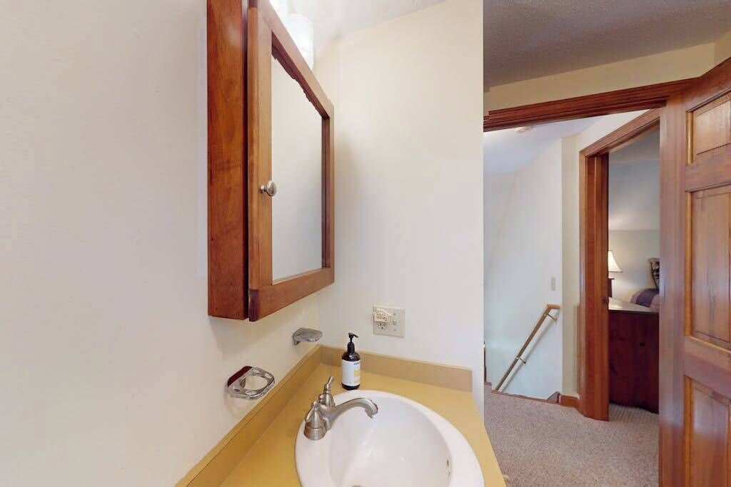 Une salle de bain avec un lavabo blanc, un miroir encadré en bois et un porte-serviettes.