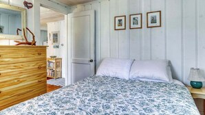 Un dormitorio con cama, cómoda, espejo y cuadros en la pared.