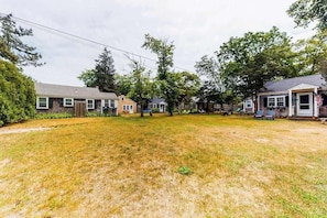 A residential area with houses, a grassy yard, and trees. - Cape-style cottage in a small village community w/ an outdoor shower (Harwich Port)