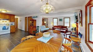 Un salón amplio con una mesa de comedor, muebles de madera y una araña.