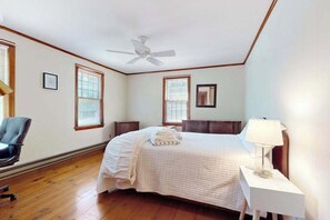 A bedroom with a bed, a ceiling fan, a nightstand with a lamp, and a chair. - Cape Getaway -walk to restaurants & shops, near bay & ocean beaches & rail trail (Eastham)