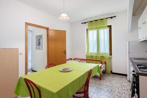 A compact room with a dining table, chairs, a small kitchenette, and a window with curtains. - Apartment '601' with Private Terrace and Shared Garden (Diano Castello)