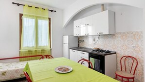 A compact kitchen with white cabinets, a gas stove, and a small dining table with a green tablecloth.