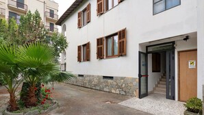Un edificio con base de piedra, contraventanas de madera y una escalera que conduce a la entrada.