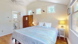 Un dormitorio con una cama, lámparas de noche, un armario de madera y una ventana.