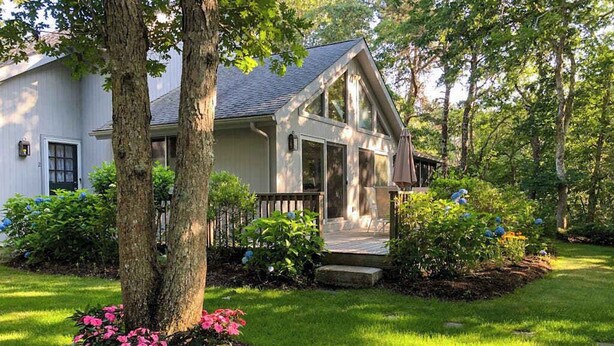 A single-story house with a front porch, surrounded by a well-maintained lawn and trees.