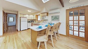 A kitchen with wooden cabinets, a central island with blue bowls, and a door labeled 'KATAMA'.