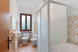 Ein Badezimmer mit Toilette, Bidet und Duschbereich.