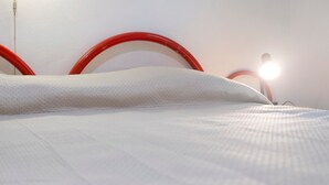 Ein Bett mit weißer Bettwäsche und einem roten Kopfteil.