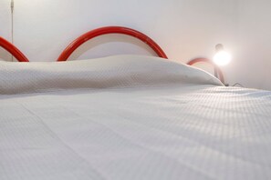 Ein Bett mit weißer Bettwäsche und einem roten Kopfteil.