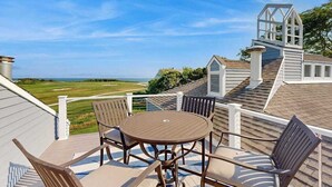 A deck with a table and chairs, overlooking a golf course. - Spacious home on golf course with 4 outdoor spaces overlooking the Sound (Mashpee)