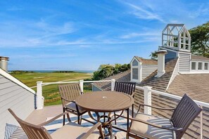 A deck with a table and chairs, overlooking a golf course. - Spacious home on golf course with 4 outdoor spaces overlooking the Sound (Mashpee)