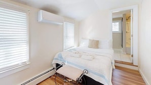 Un dormitorio con cama, calefactor y espejo.