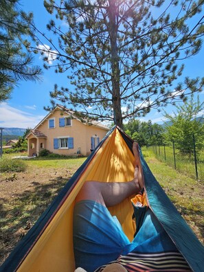 A hammock between trees with a house in the background. - Family home with river access and large lot, pets welcome (Garde-Colombe)