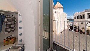 A balcony with a view of a white building with a dome, a metal railing, and a hanging garment rack. - Fantasy House Suites (Forio)