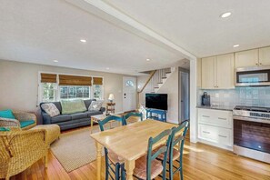 A living room with a sofa, TV, and dining table. - Cozy retreat near beaches with washer/dryer, AC, games, patio & yard (Falmouth)
