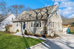 A single-story house with a front porch, a small front yard, and a clear sky. - Cozy retreat near beaches with washer/dryer, AC, games, patio & yard (Falmouth)