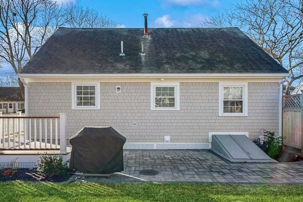 A two-story house with a brick exterior, a covered patio, and a small deck.