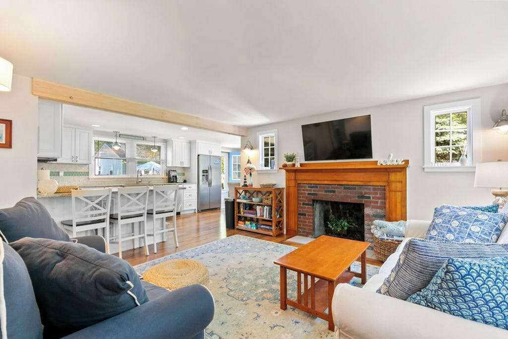 Een woonkamer met een open haard, een televisie en een keuken op de achtergrond.