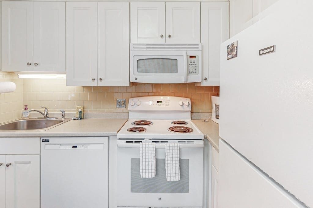 A kitchen with white cabinets, a microwave, a stove, and a dishwasher.
