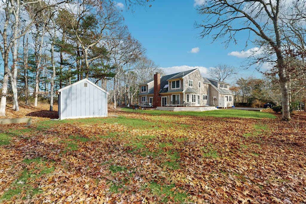 Une grande maison à deux étages, dotée d’une pelouse bien entretenue et d’un abri de jardin situé au premier plan.