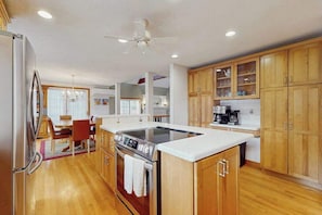 A kitchen with wooden cabinets, a built-in oven, a stovetop, and a dining area with a table and chairs.