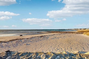 A beach with a rocky foreground, a sandy beach, and a clear sky.