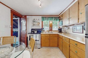 A compact kitchen with wooden cabinets, a stove, a sink, and a refrigerator.