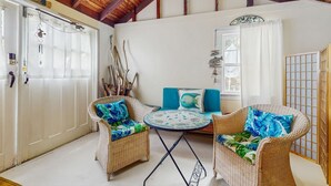 Una habitación con muebles de mimbre, una mesa redonda y techo de madera.