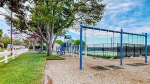 Ein Spielplatz mit Schaukeln, einer Rutsche und einer Kletterkonstruktion.
