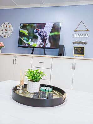 Ein an der Wand montierter Fernseher zeigt eine Naturansicht, ein Willkommensschild und eine dekorative Wandleiste.