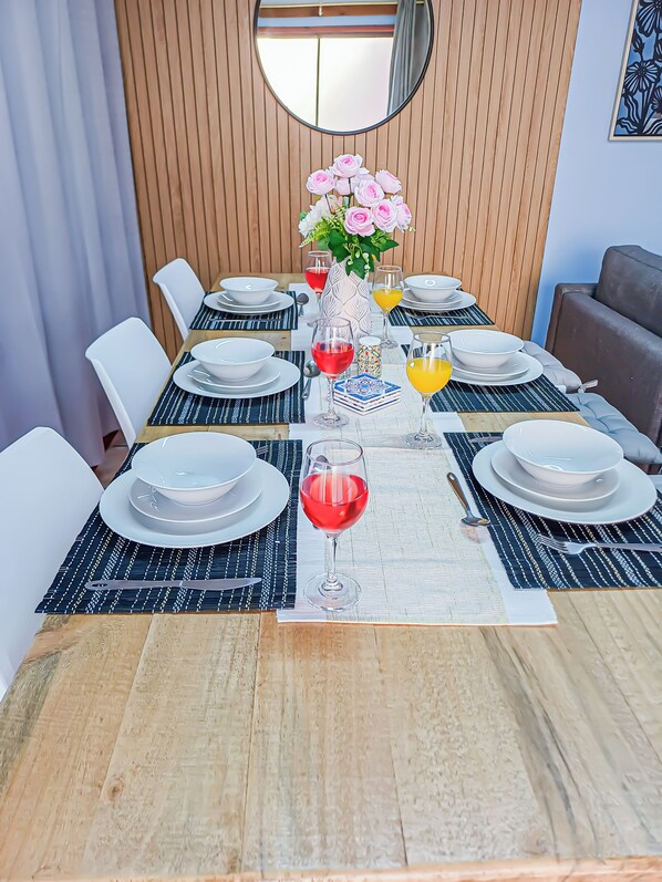 A dining table set with plates, glasses, and a vase of flowers.