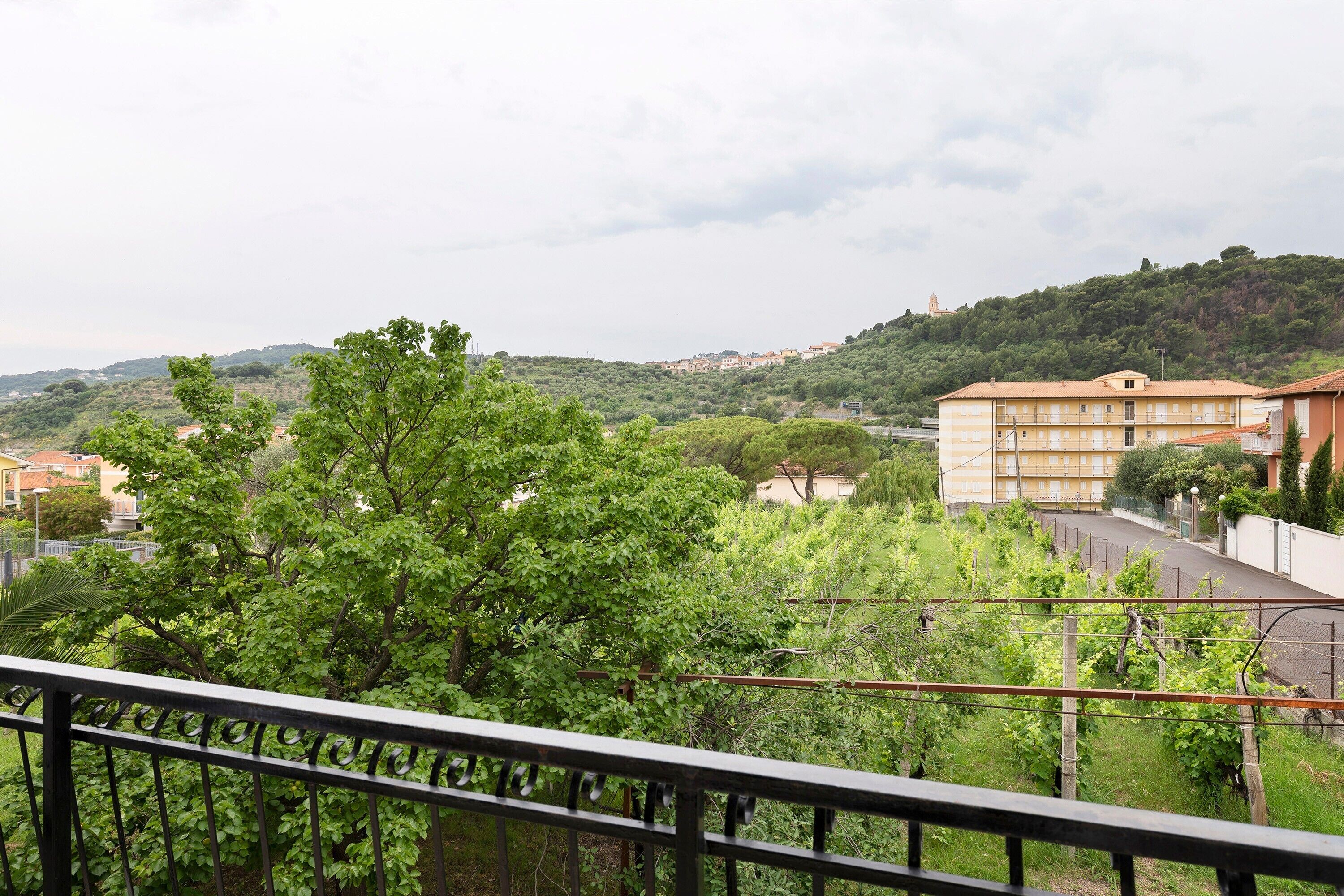 Ein Balkon mit Blick auf eine Hügellandschaft, Gebäude und einen klaren Himmel.