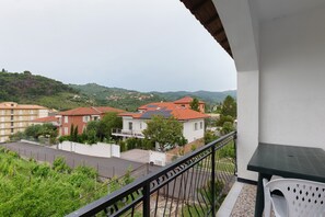 Ein Balkon mit Blick auf Wohnhäuser und Hügel.