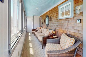 A corridor with wicker furniture, a mirror, and a light fixture. - Inviting condo near famed beaches/trails with screened porch & washer/dryer (Provincetown)