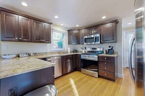 Una cocina moderna con armarios de madera oscura, electrodomésticos de acero inoxidable y encimera de granito.
