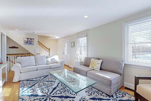 Una sala de estar con un sofá blanco, un sofá gris y una mesa de centro de vidrio.