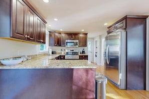 A modern kitchen with dark wooden cabinets, stainless steel appliances, and a granite countertop.
